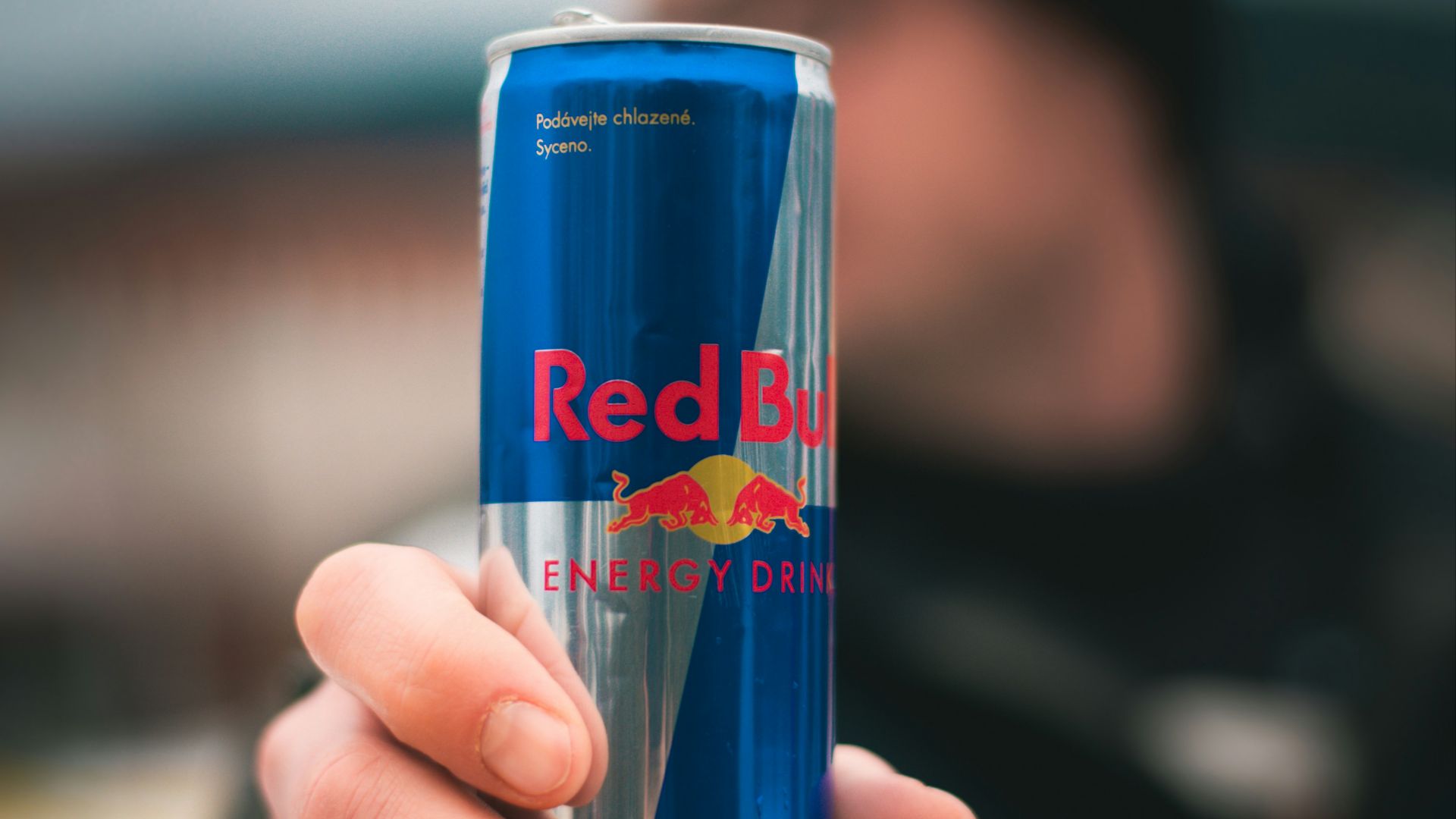 person holding red bull energy drink can