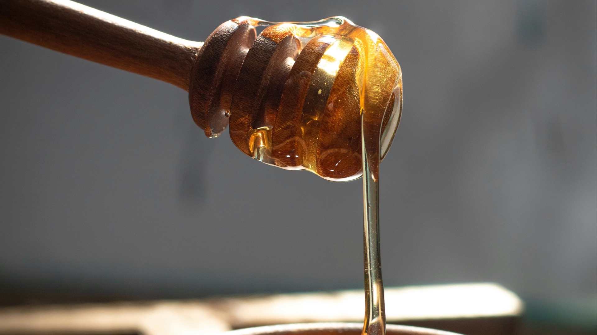 a honey dip being poured into a wooden bowl