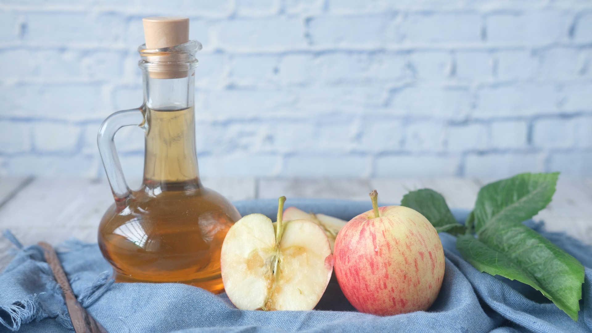 clear glass bottle with red liquid beside sliced lemon on blue textile
