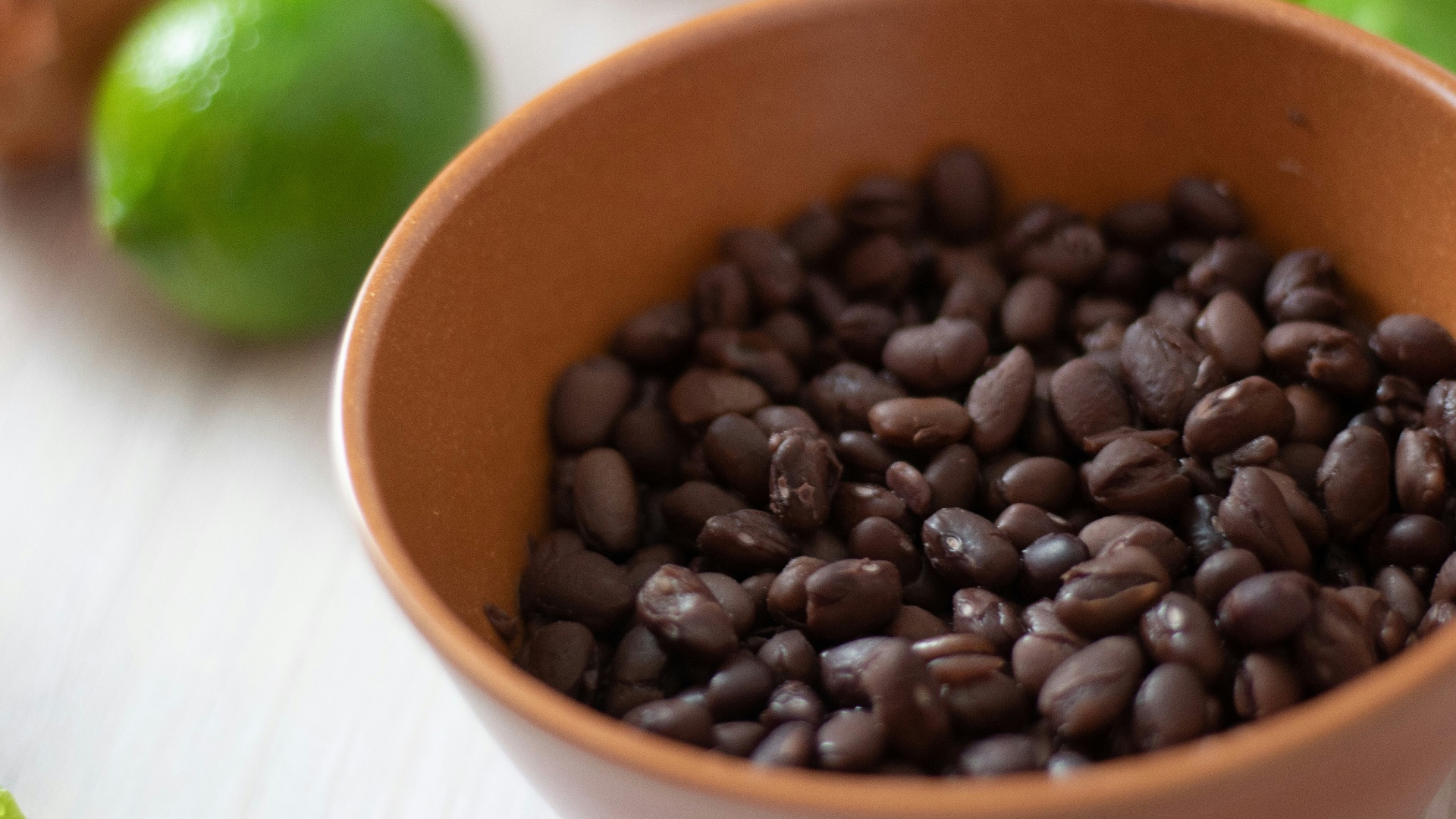 a bowl filled with black beans next to limes