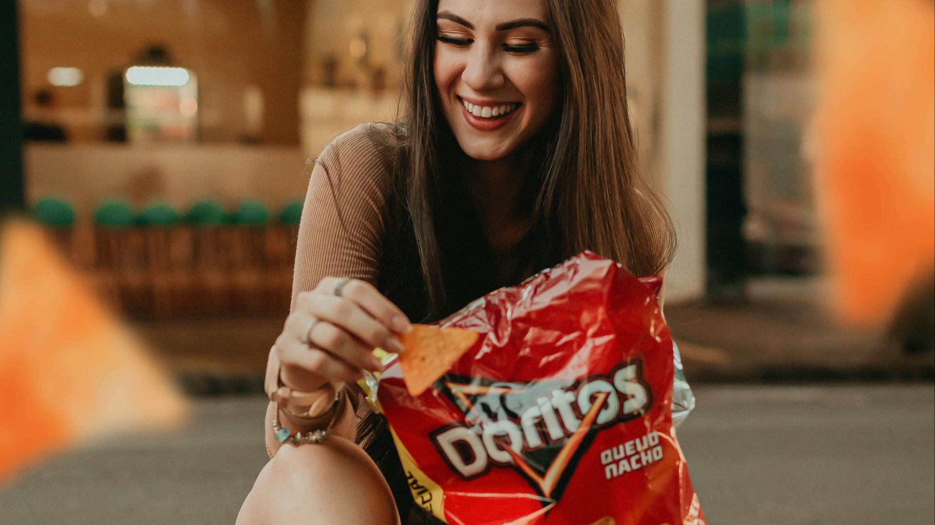 woman in black shirt sitting on the street holding red plastic pack