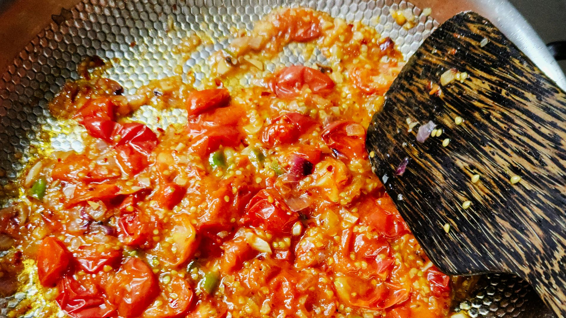 Tomatoes and spices are cooking in a pan.