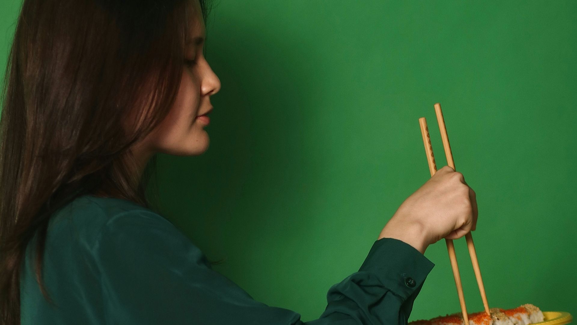 a woman holding a plate of food with chopsticks