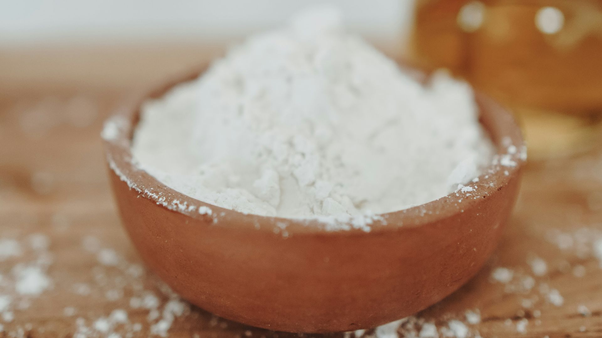 a wooden bowl filled with white powder next to a bottle of honey