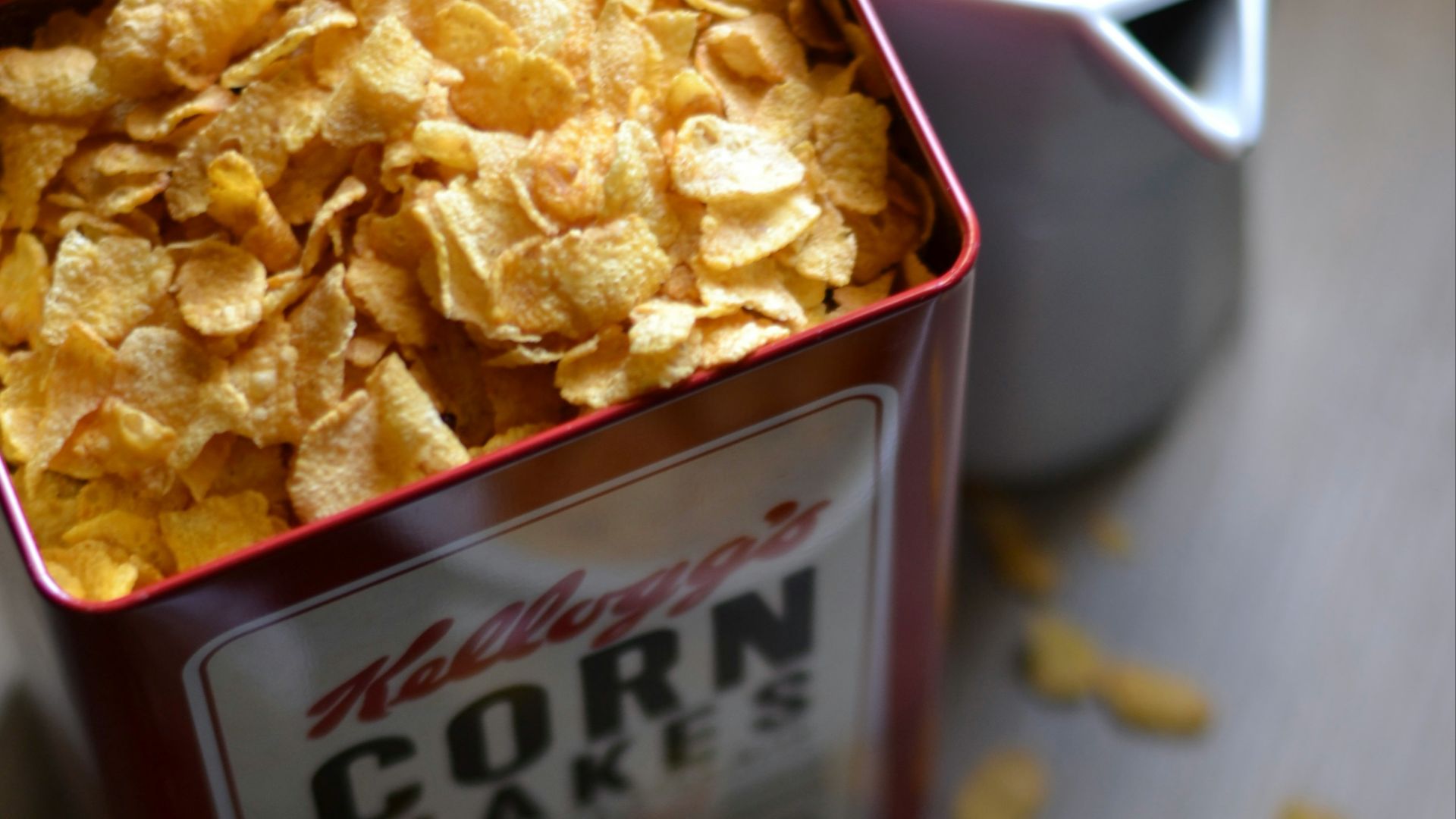 A box of corn flakes next to a bowl of cereal
