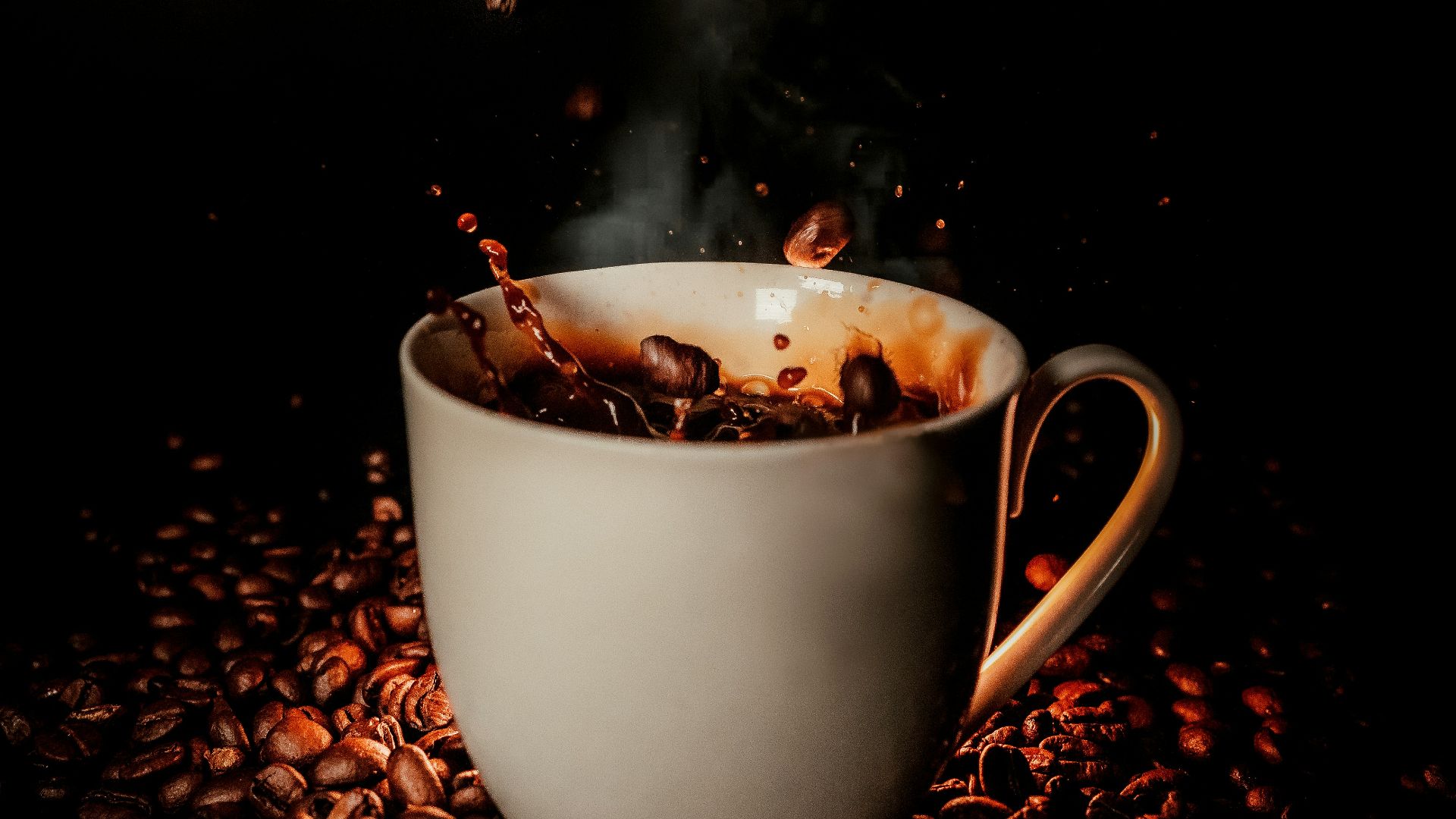 white ceramic teacup with coffee beans