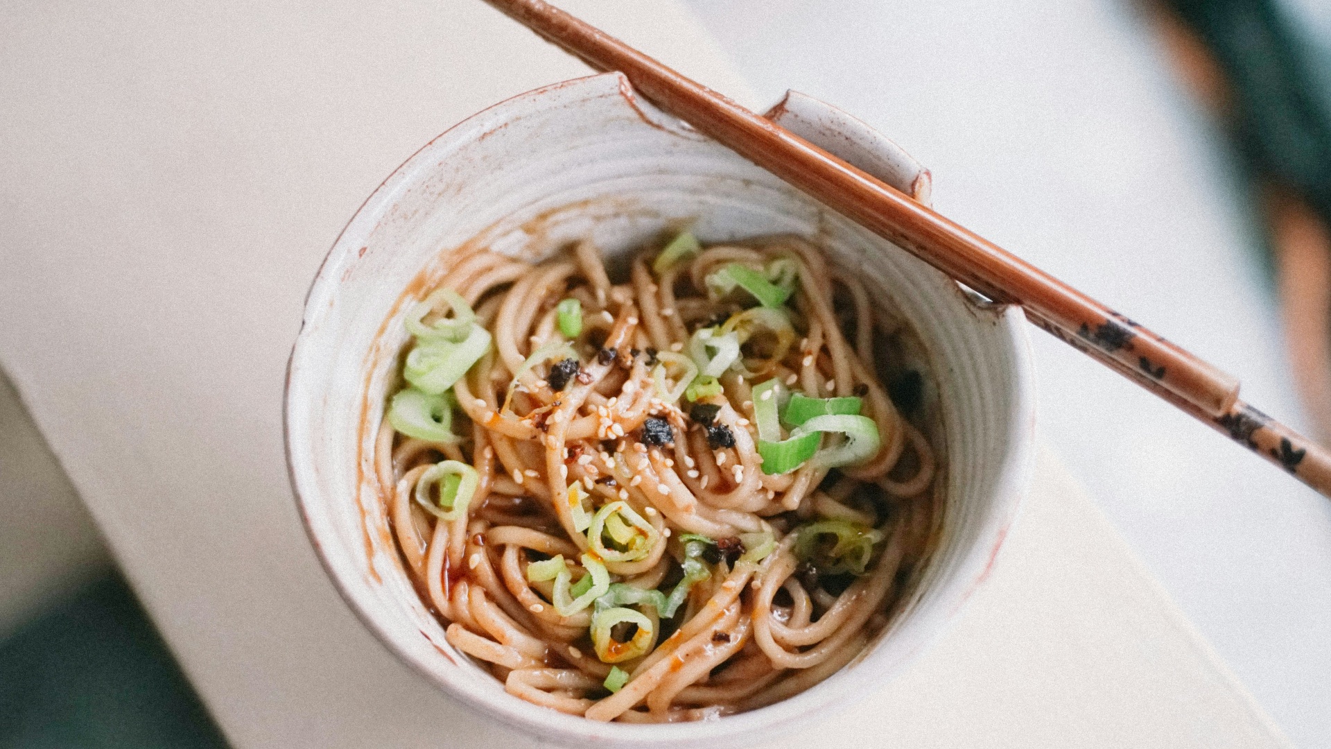 white ceramic bowl with noodles and chopsticks