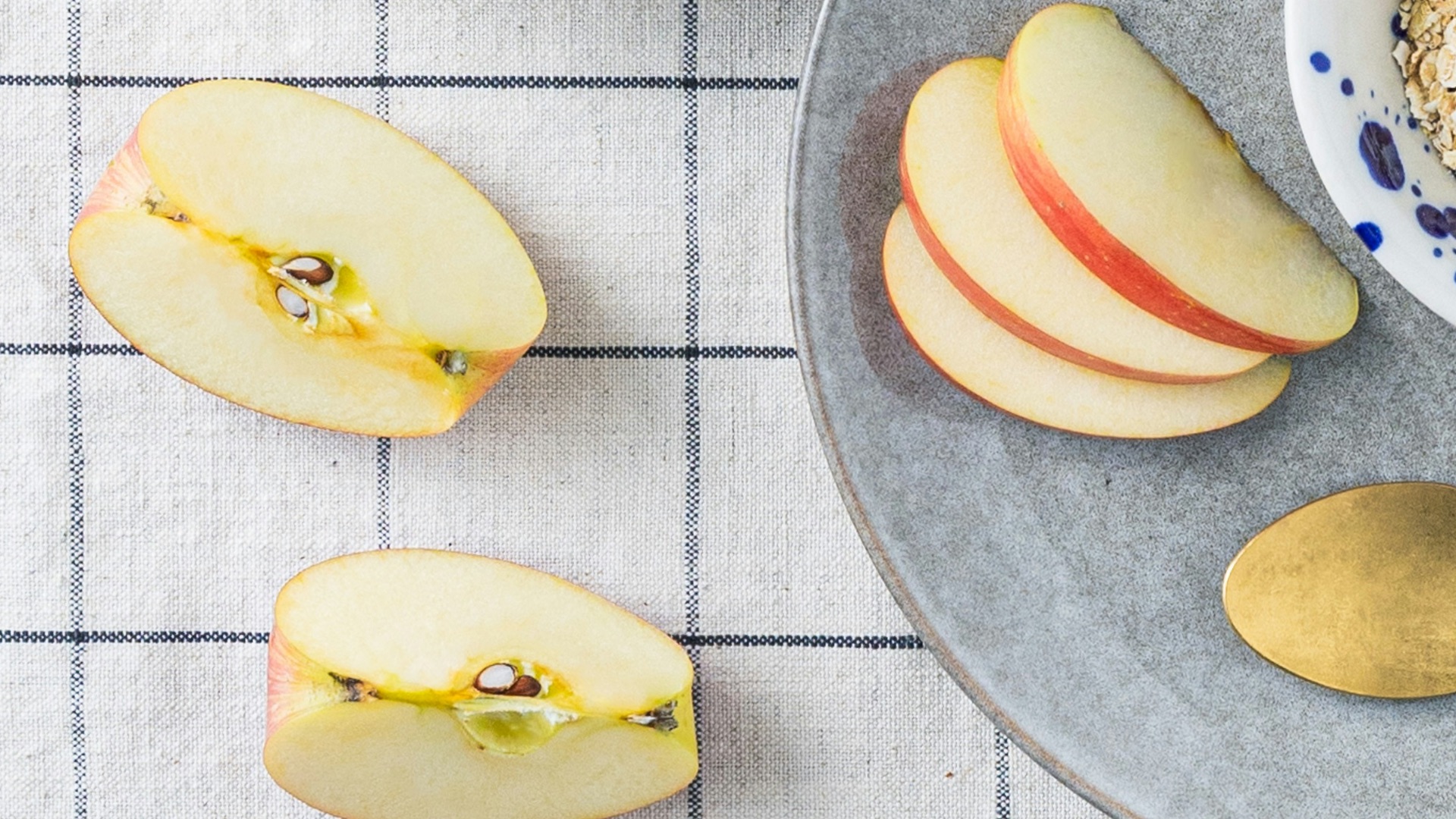 a bowl of oatmeal, apple slices, and a spoon on a