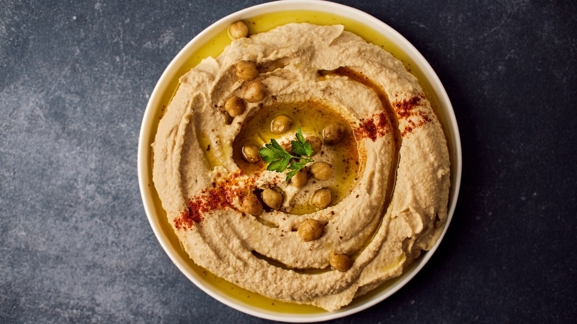 a bowl of hummus with a garnish on top