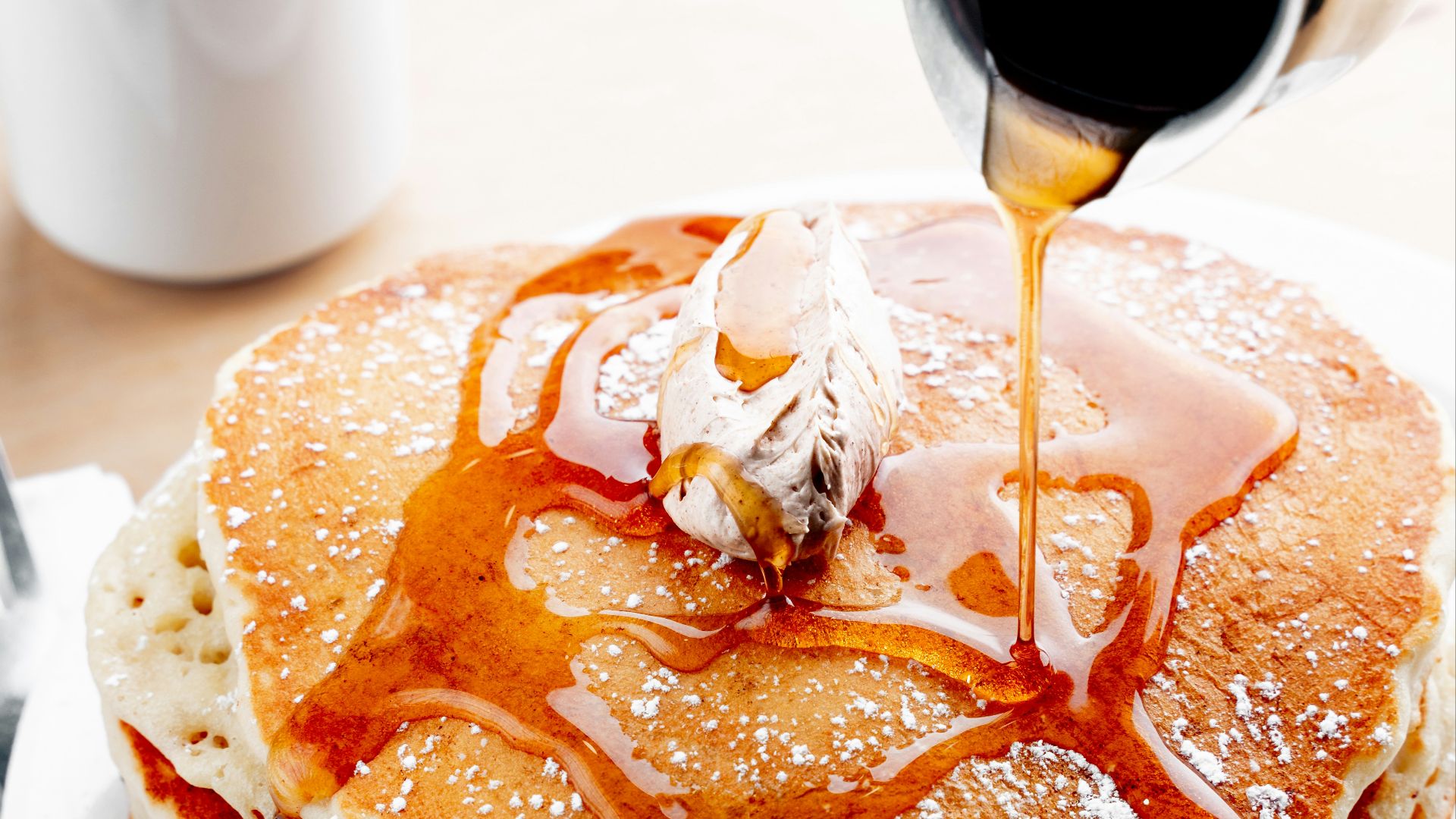 a stack of pancakes with syrup being drizzled on top