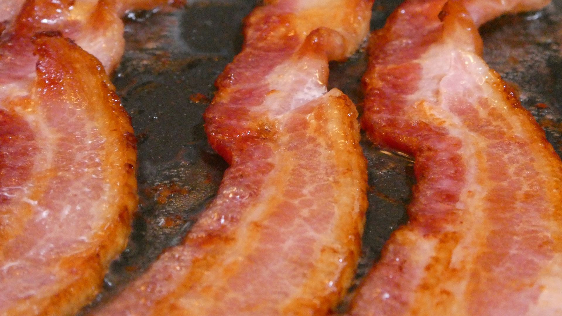 bacon is being cooked in a frying pan