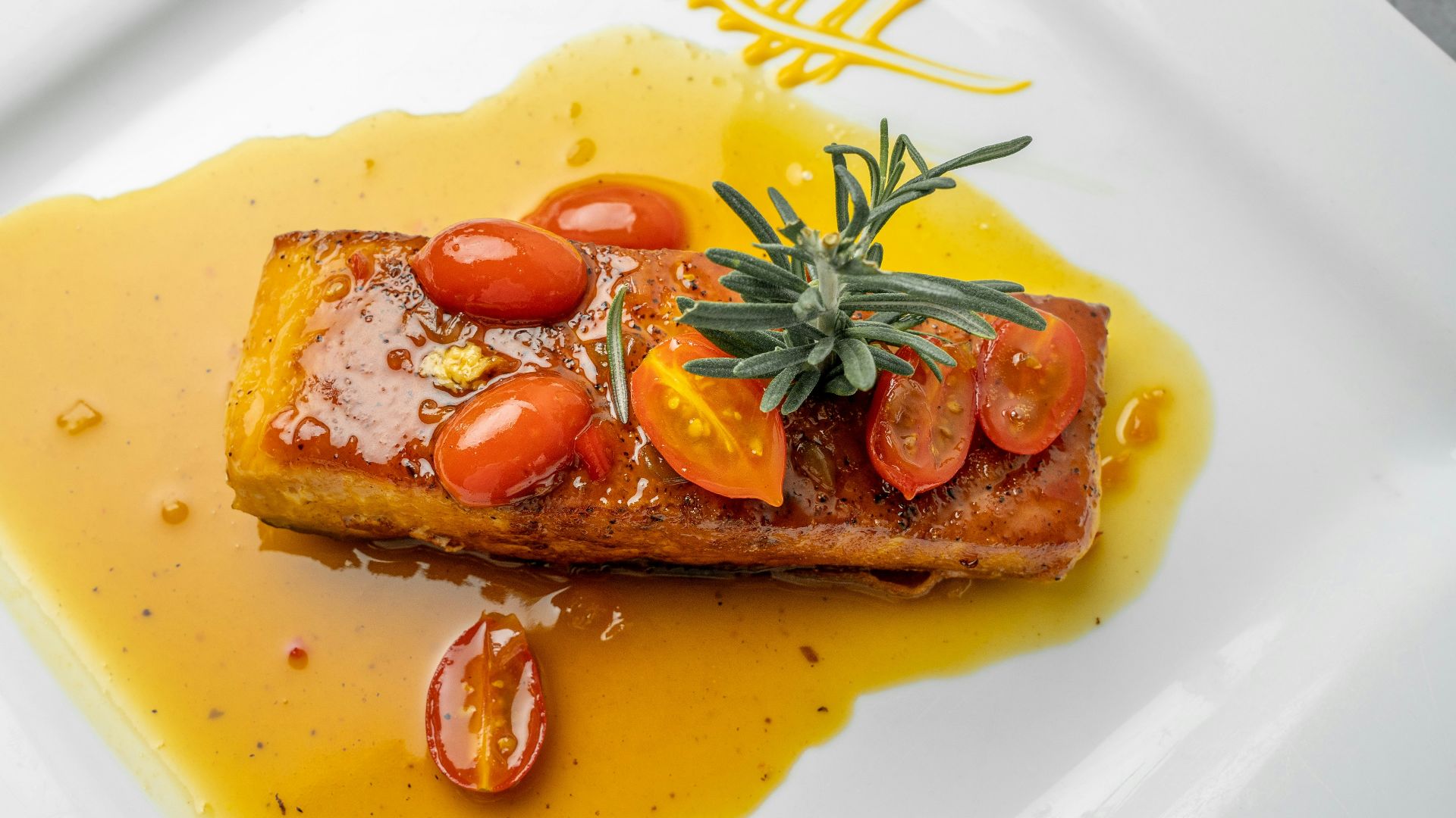 a white plate topped with a piece of meat covered in tomatoes