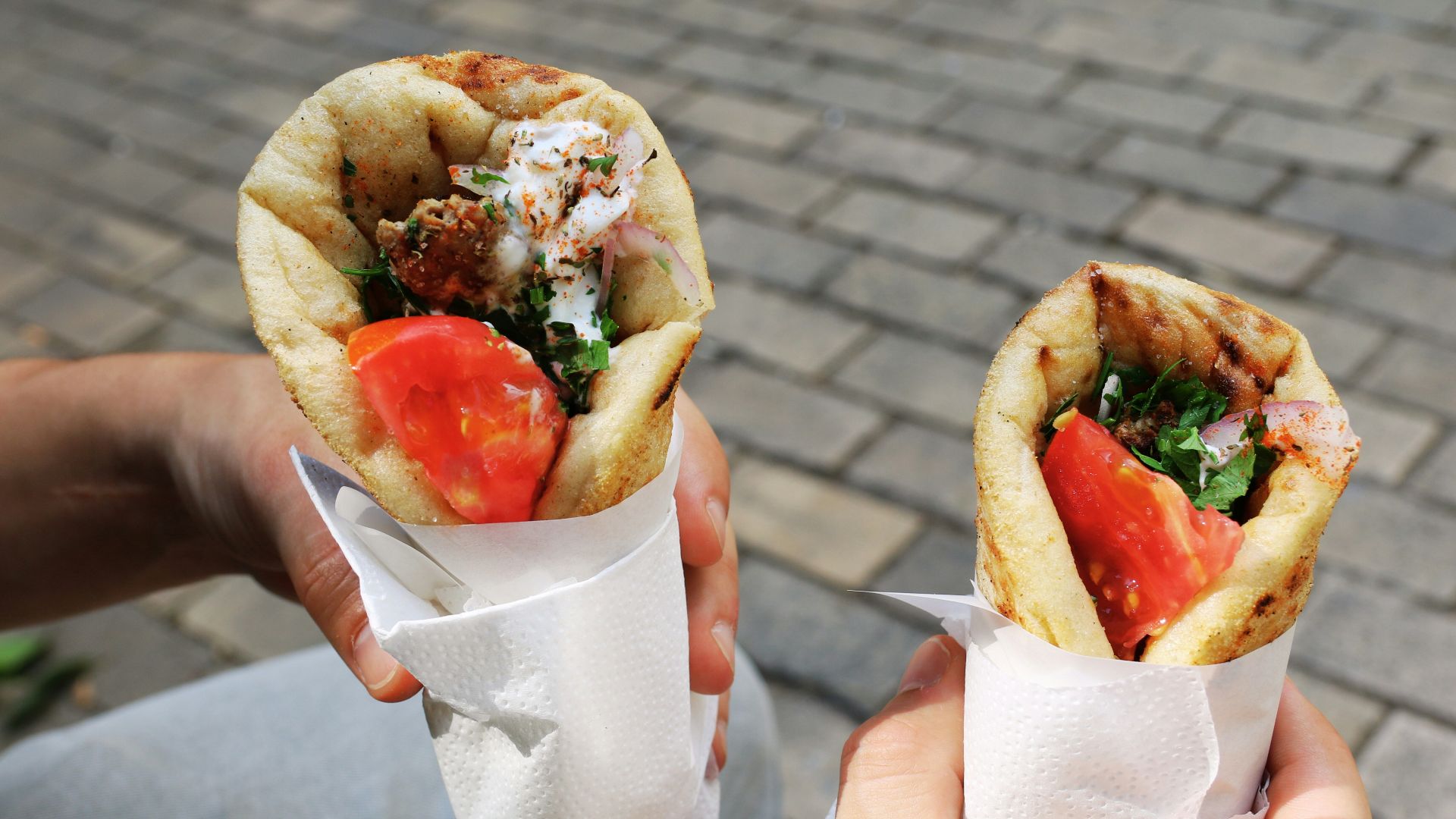 A person holding two sandwiches in their hands