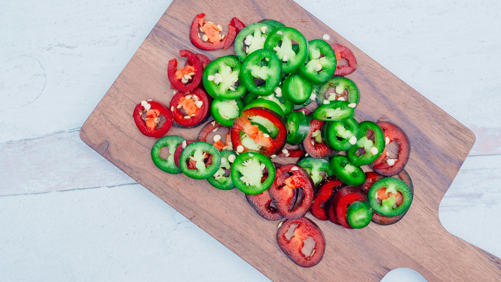 a wooden cutting board topped with green and red peppers