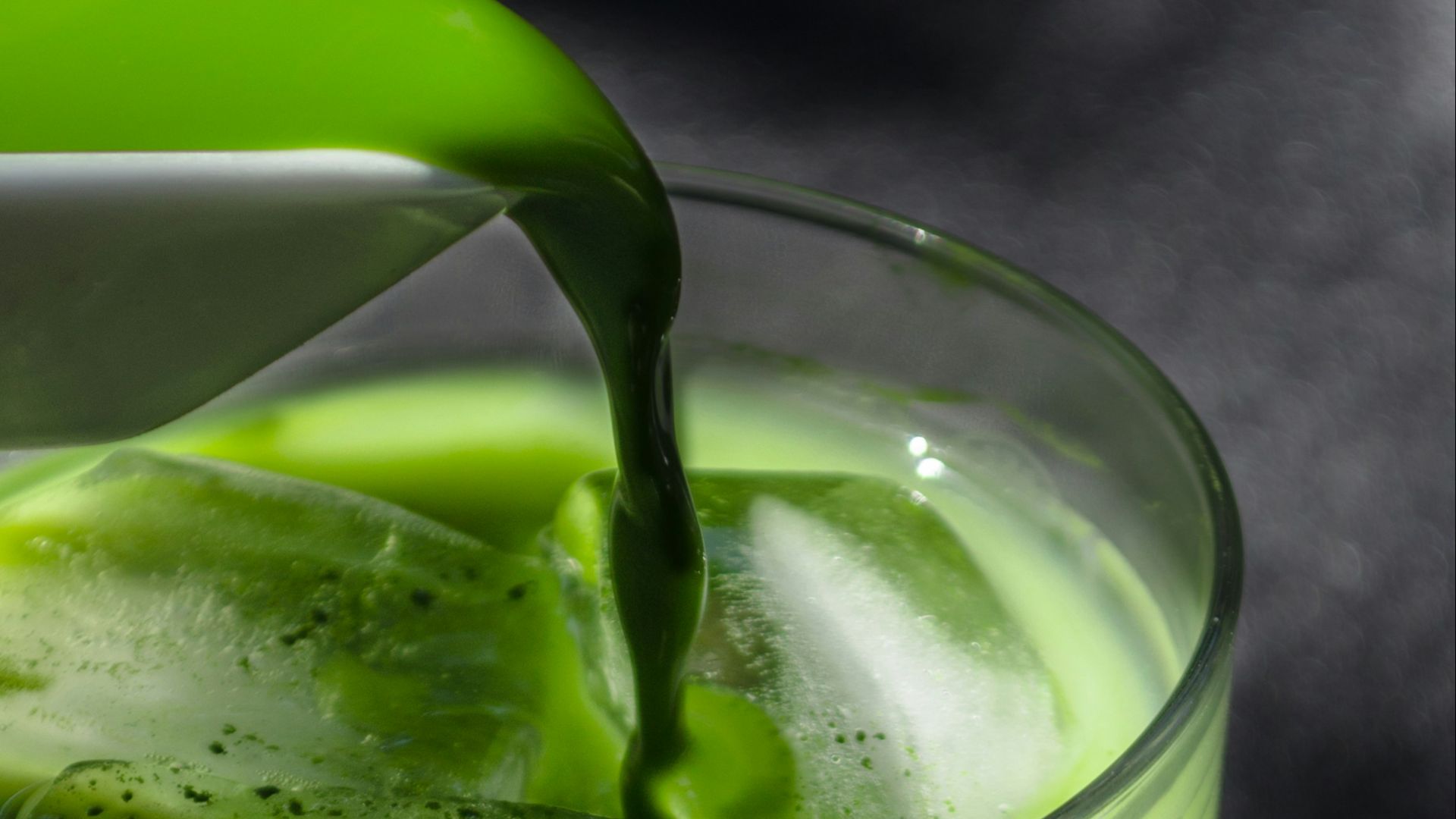 a pitcher pouring green liquid into a glass