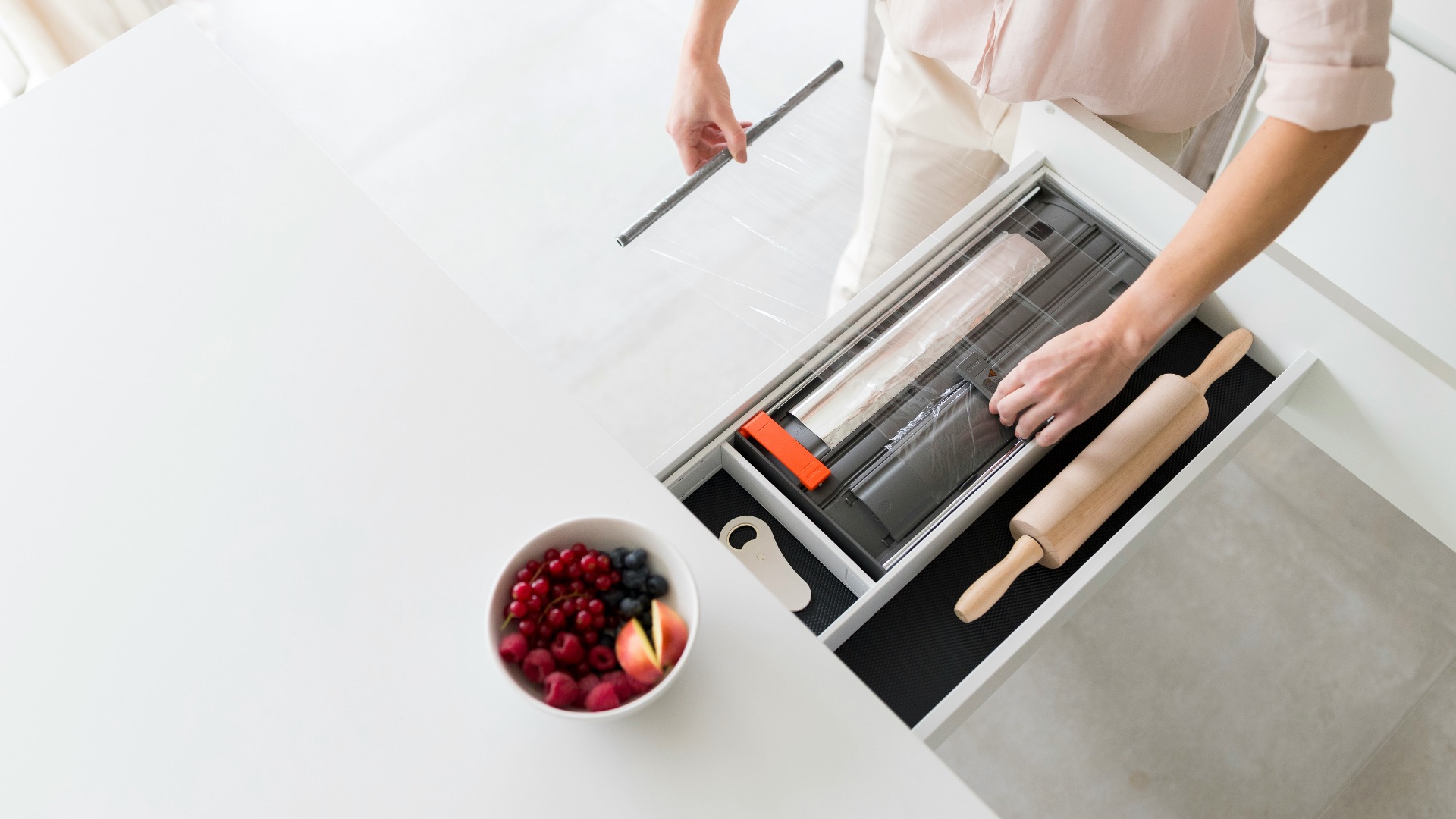 a person standing over a white table with a bowl of fruit