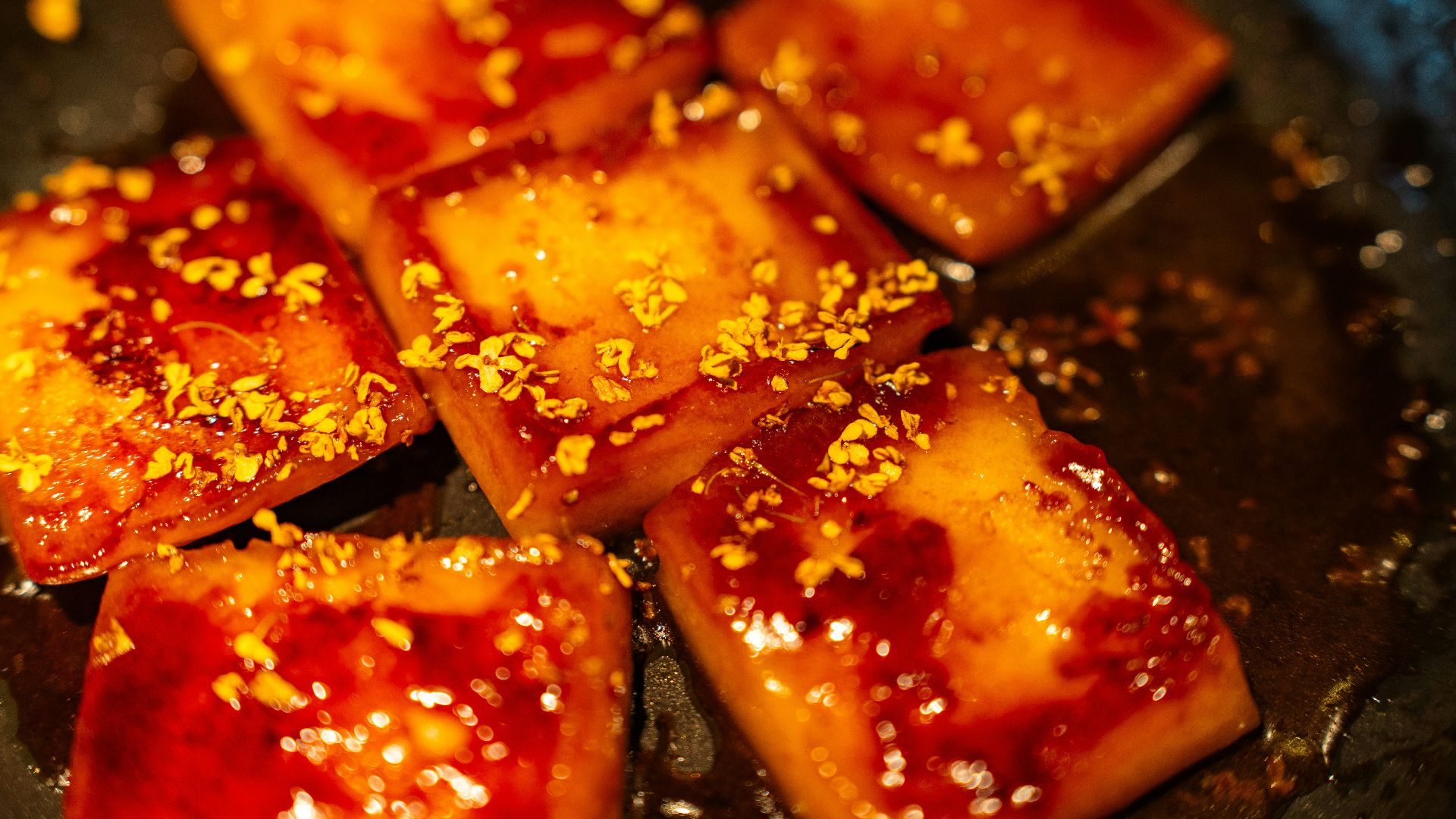 Square pieces of glazed food sprinkled with orange zest.