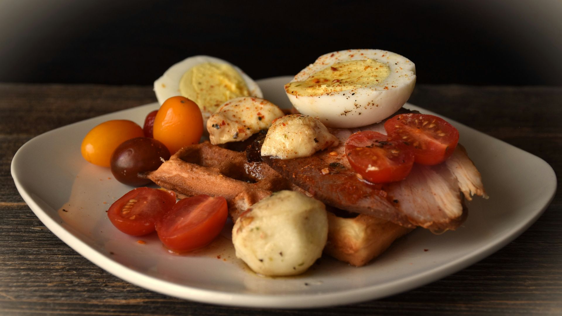 Savory waffle topped with chicken, tomato, and egg.