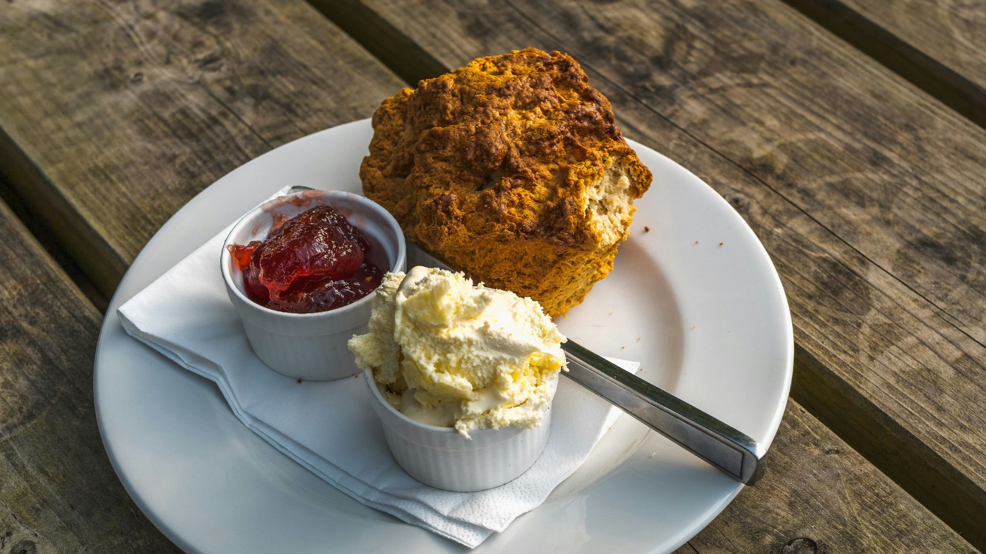 Scone with jam and cream on a wooden table