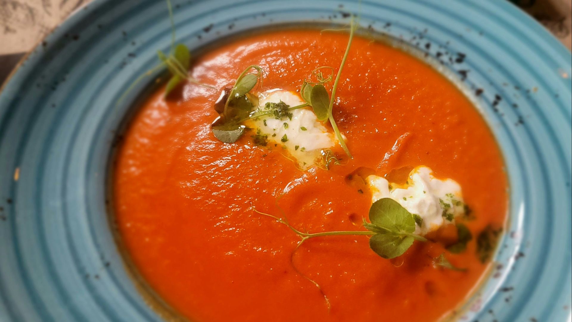 Tomato soup with a swirl of cream and greens.