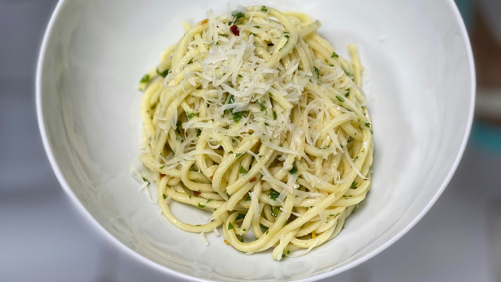 A person holding a bowl of spaghetti in their hand