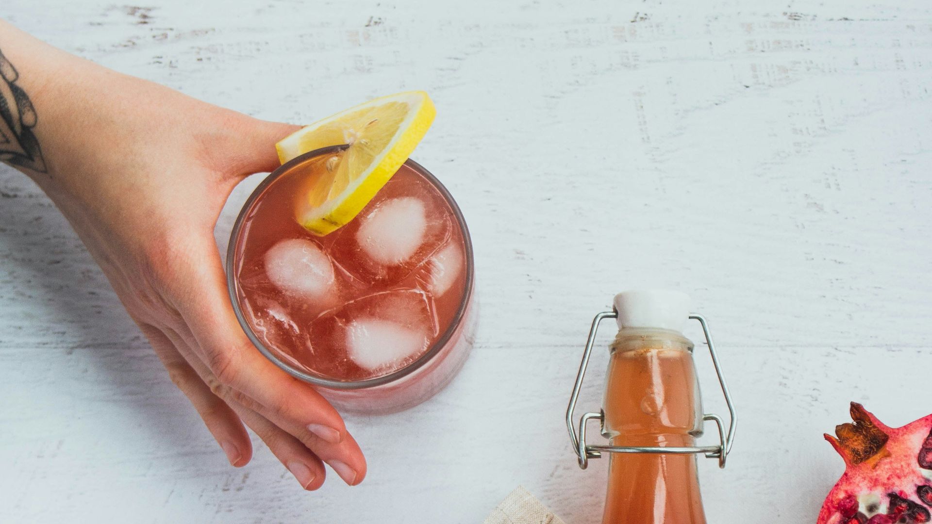a bottle of pomegranate next to a glass of juice