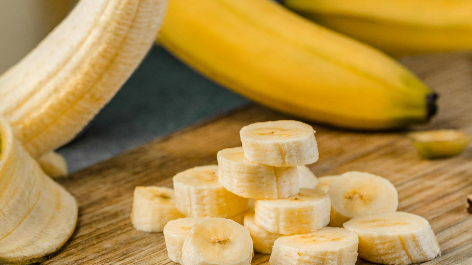 yellow banana fruit on brown wooden chopping board