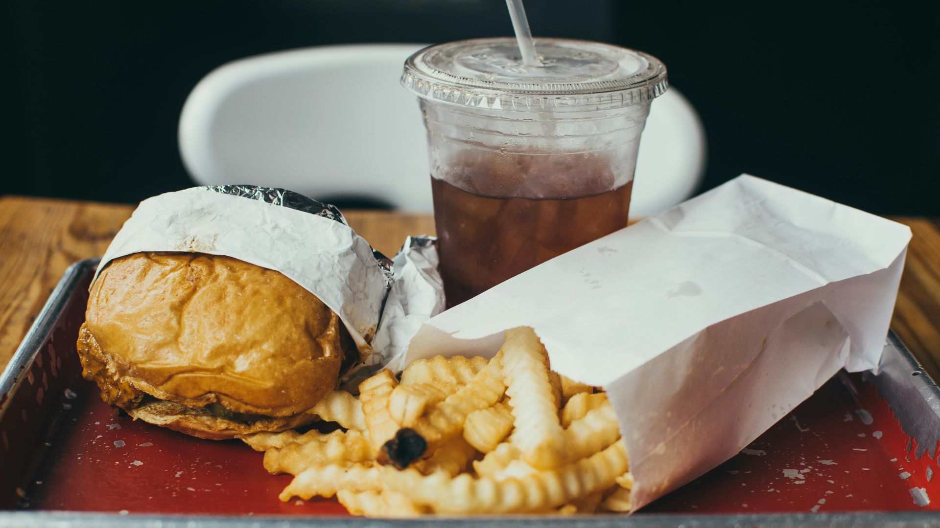 burger beside fried potatoes with drinking glass