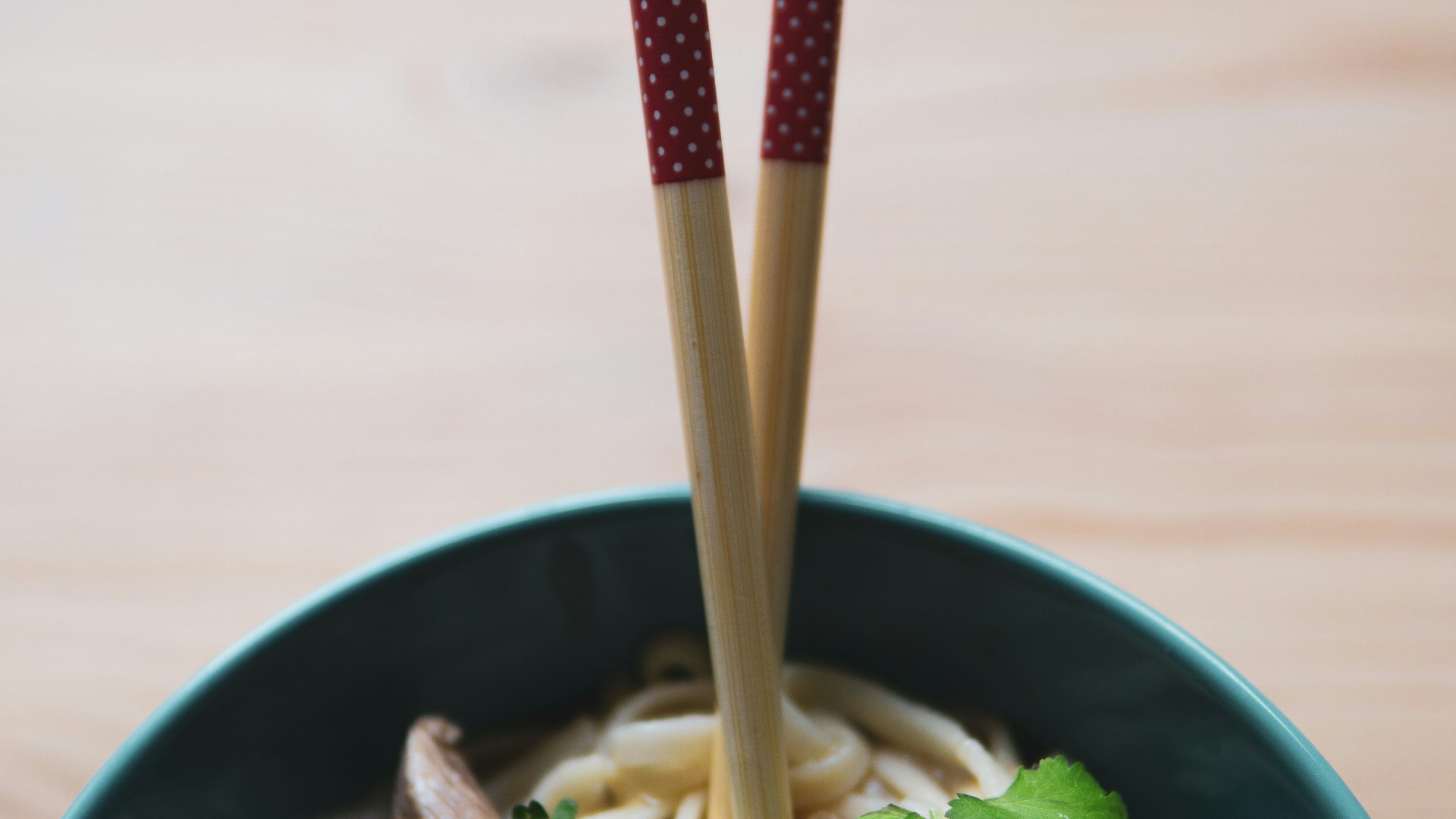 green and white ceramic bowl with brown chopsticks