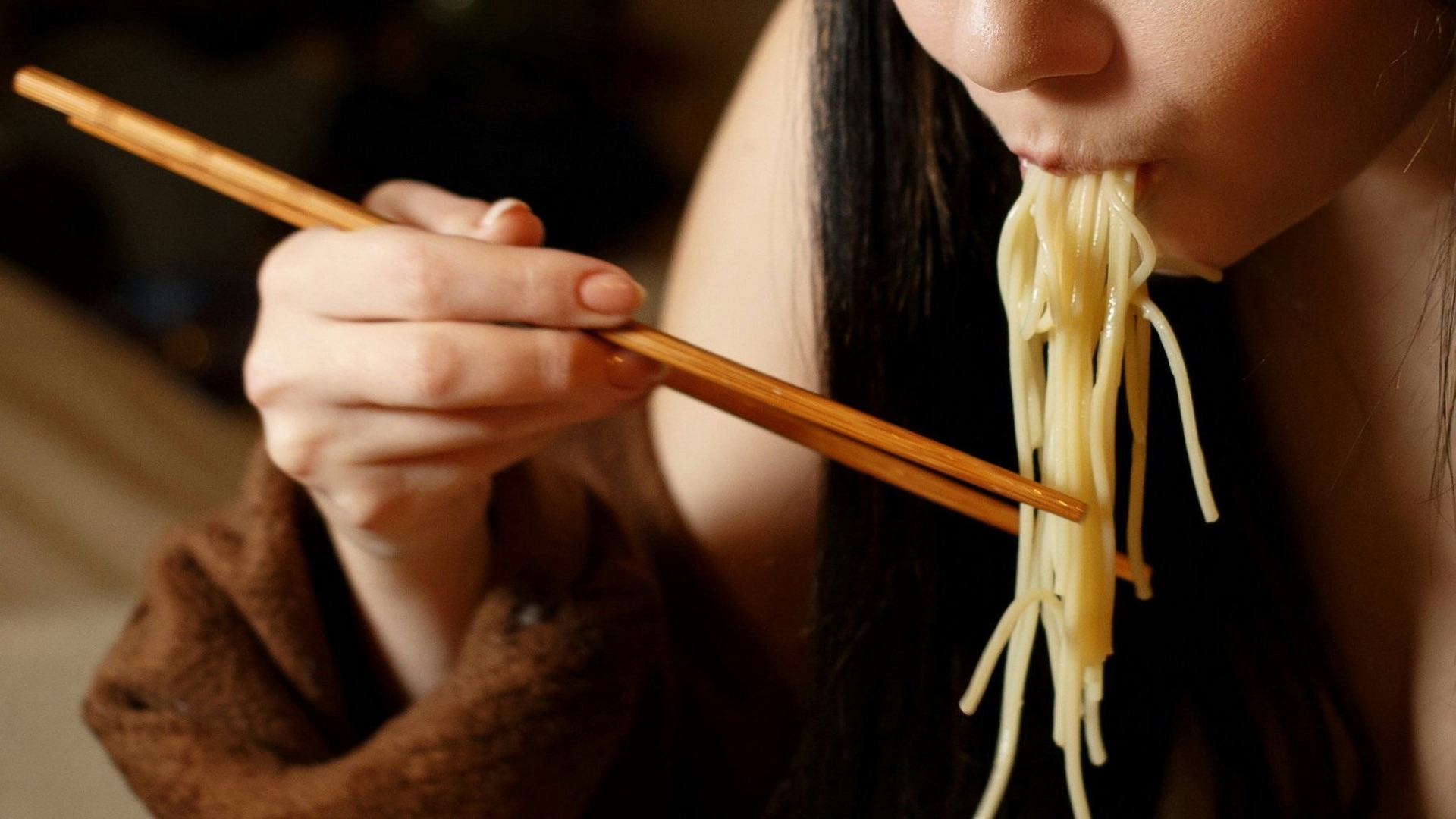 a woman eating a bowl of noodles with chopsticks