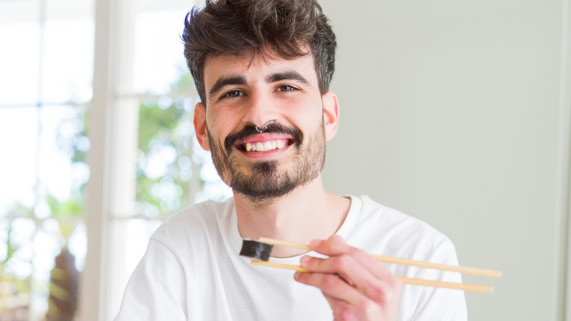 man in white crew neck t-shirt holding white chopsticks
