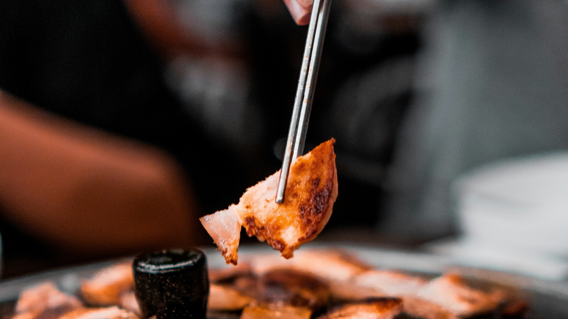 person picking grilled meat from grill using sticks