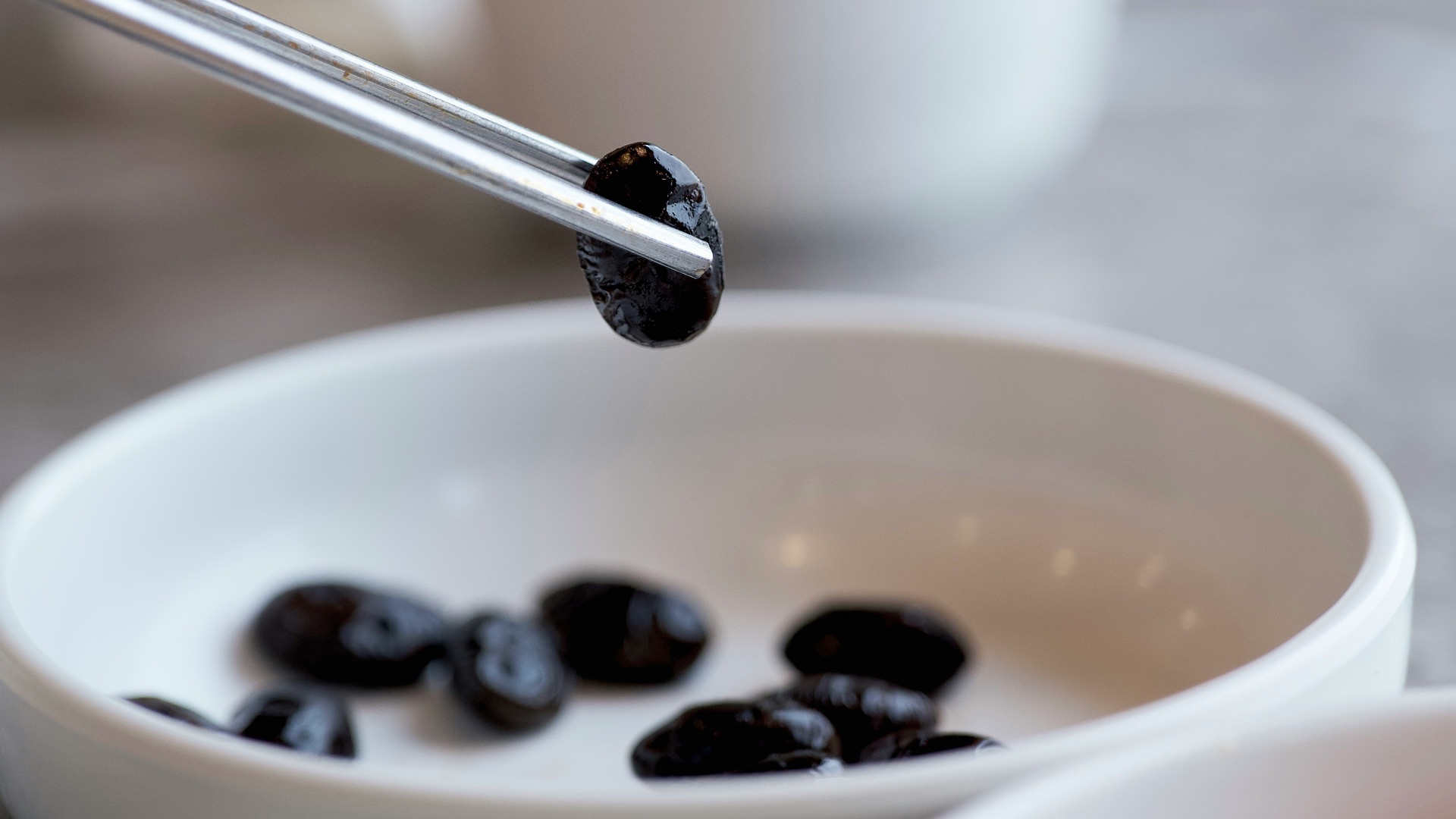 a bowl of black olives and a cup of coffee