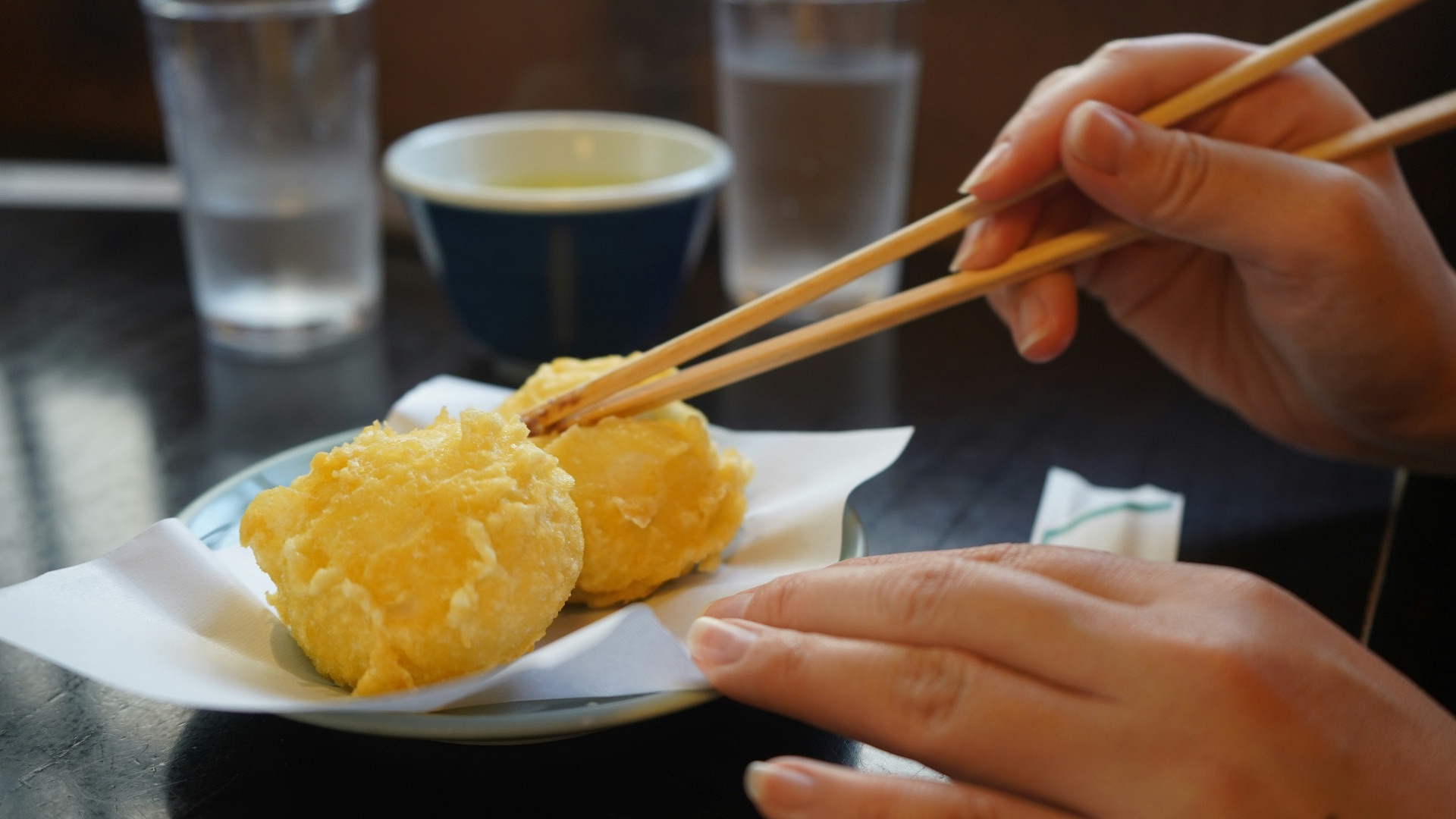 Person using chopsticks to pick up fried food.