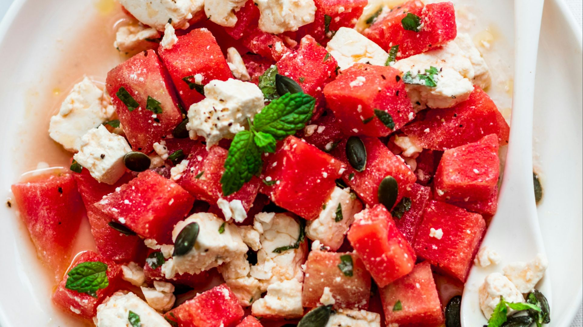a plate of watermelon and feta salad next to a glass of water