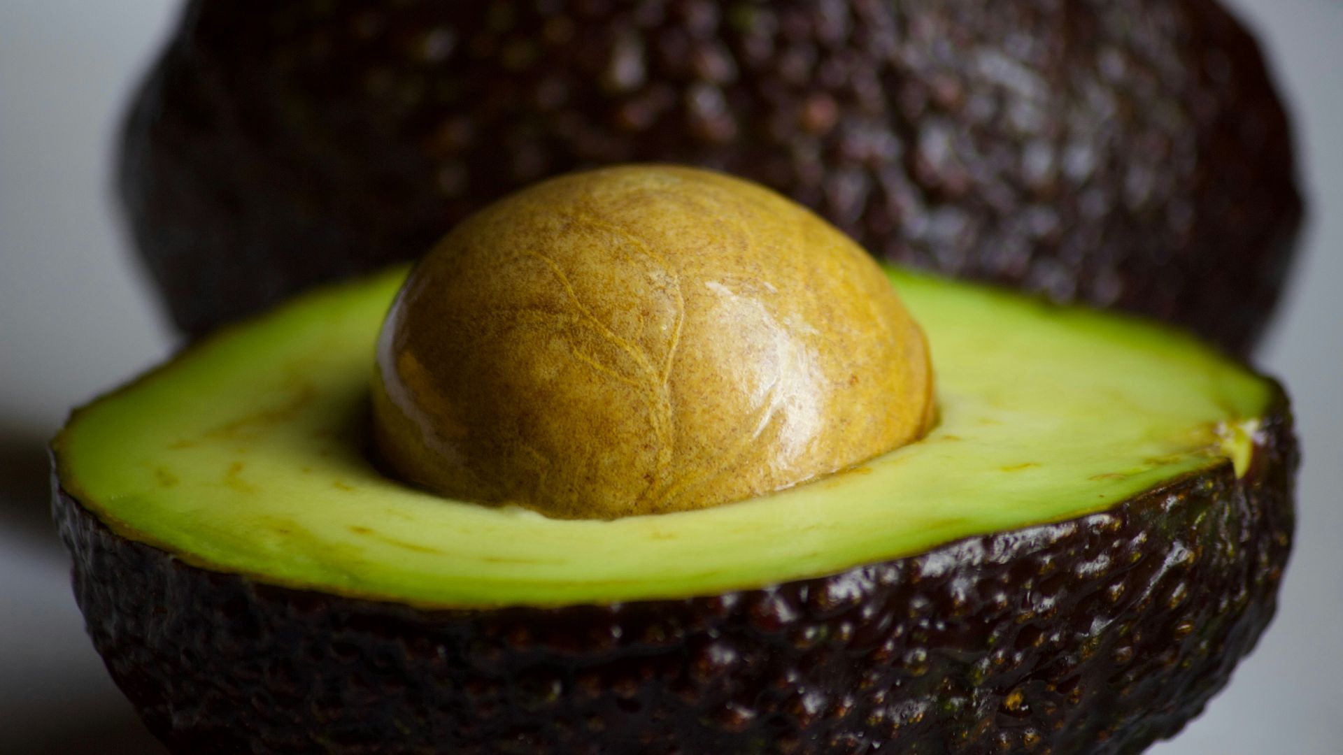 An avocado cut in half with a whole avocado in the middle