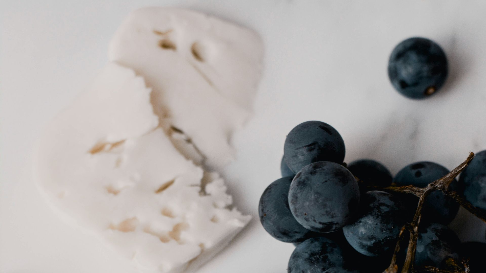 grapes, crackers and cheese on a marble surface