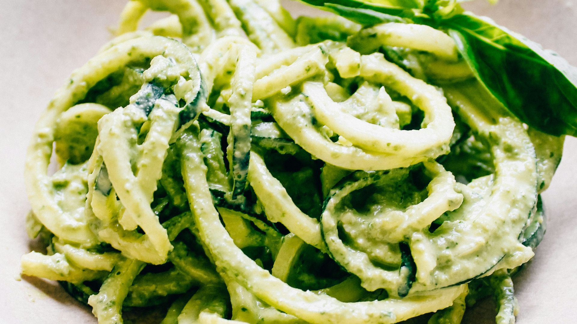 a white bowl filled with pesto pasta on top of a table