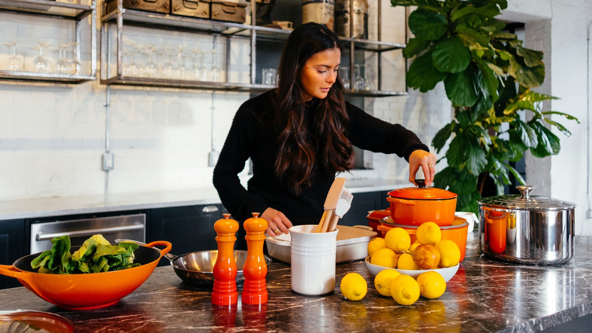 woman standing in front of fruits holding pot's lid