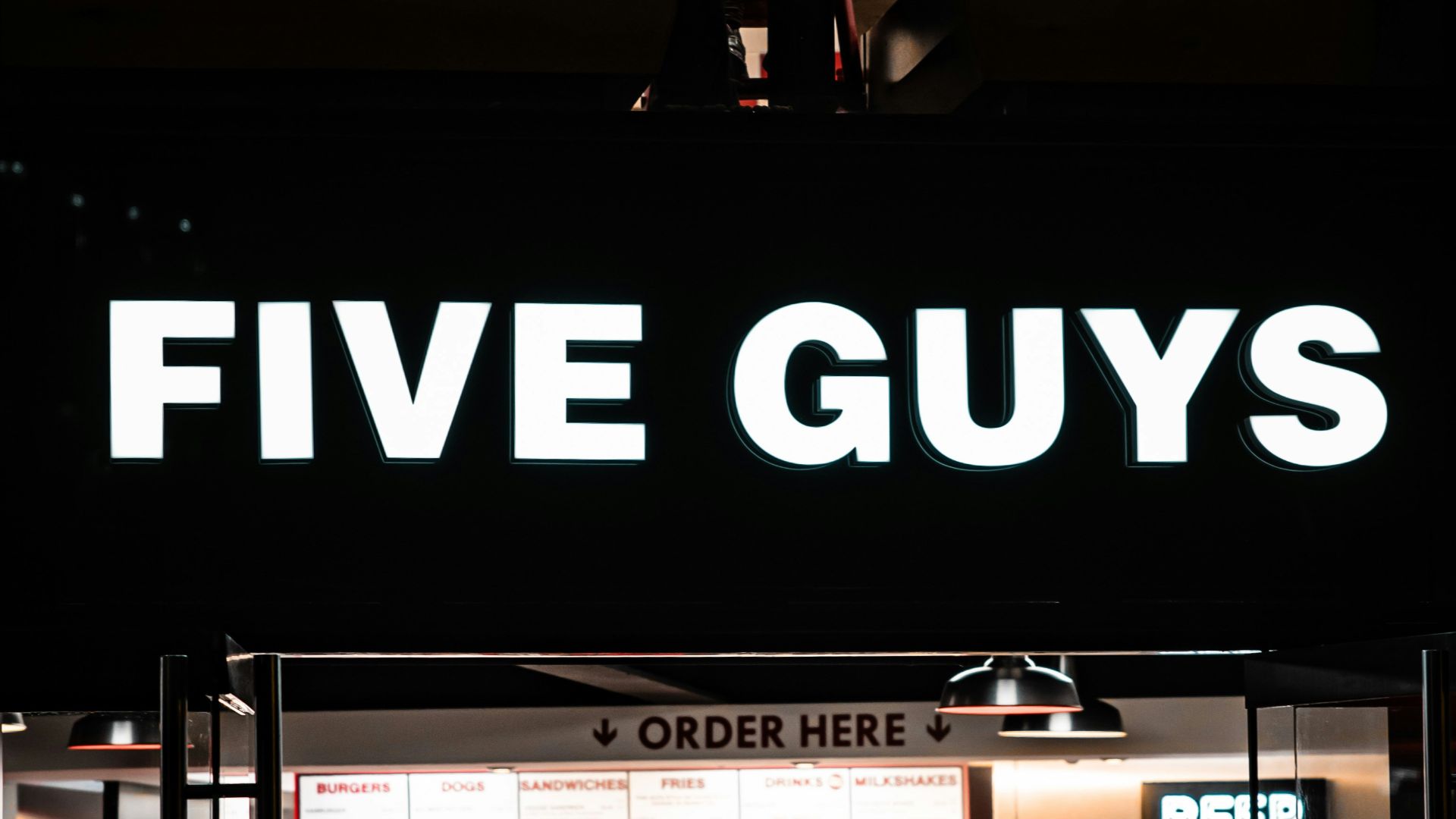 a five guys restaurant is lit up at night