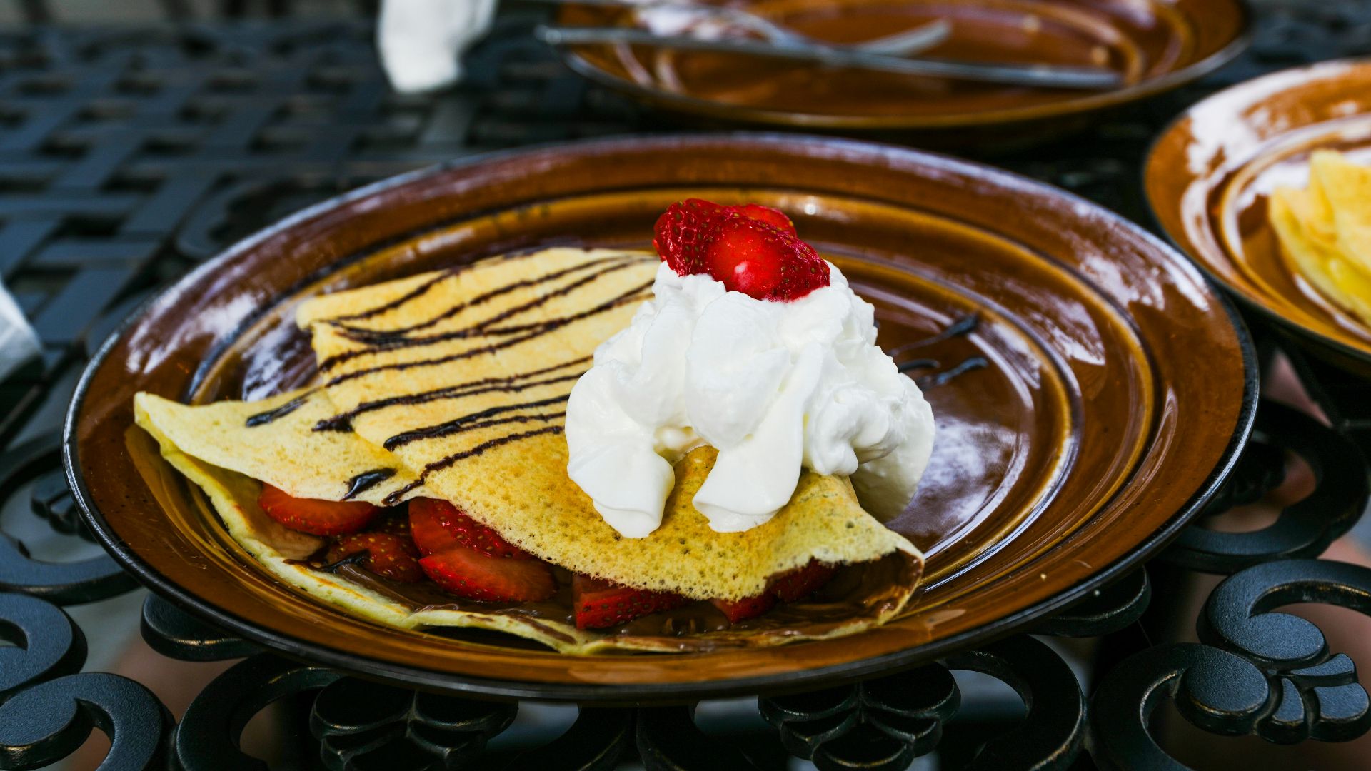 a plate of pancakes with whipped cream and strawberries