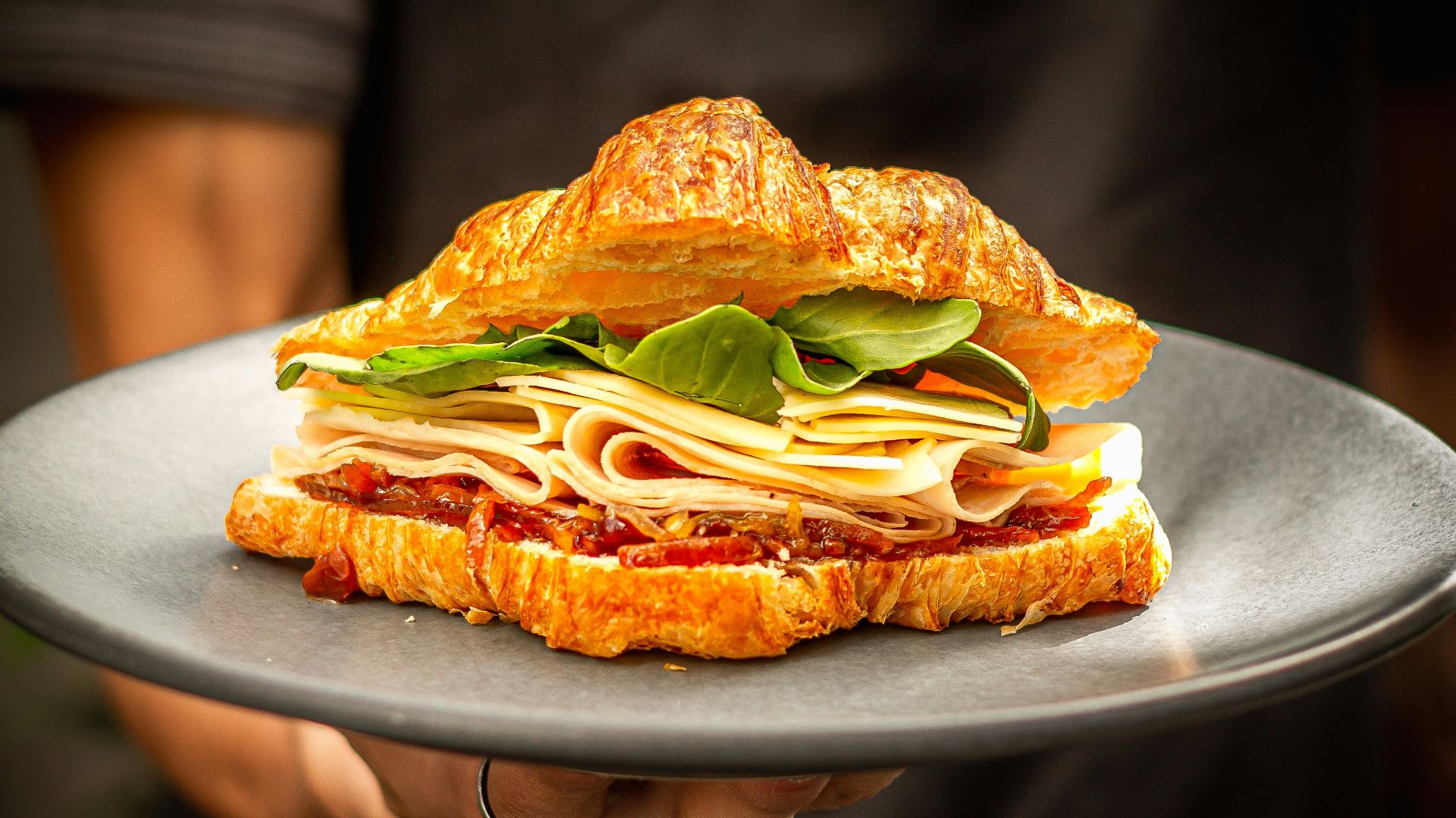 a person holding a plate with a sandwich on it