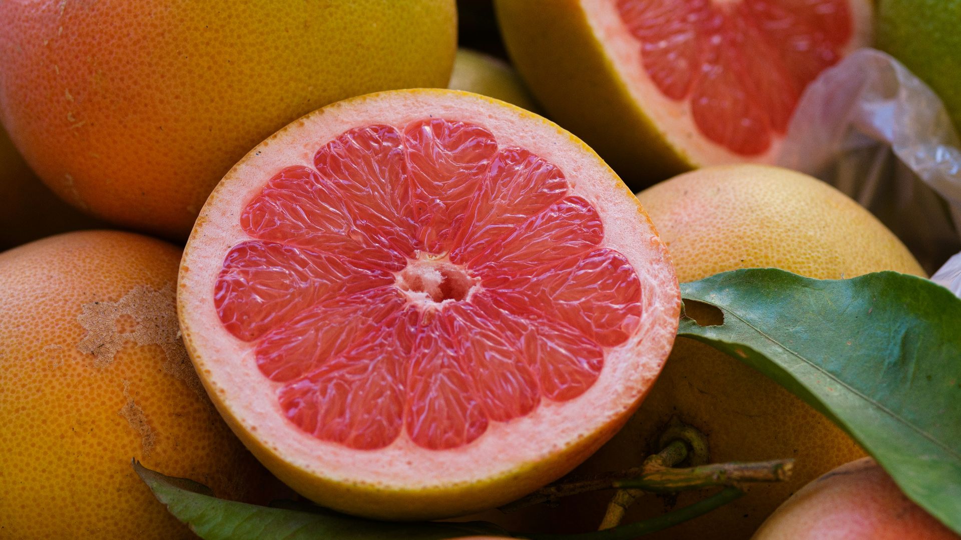 a pile of grapefruits with one cut in half