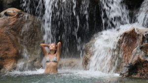 sexy-beautiful-multicultural-woman-bathing-and-swimming-under-waterfall-in--1536871663307-300x169.jpg