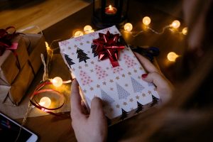 person-holding-gift-box-with-red-ribbon-beside-string-lights-1687049-300x200.jpg