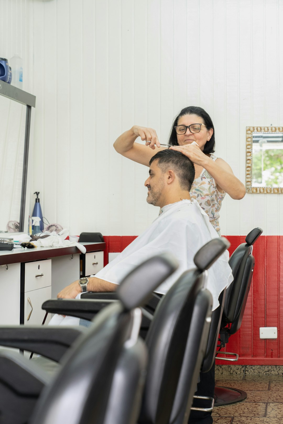 a man getting his hair cut by a woman