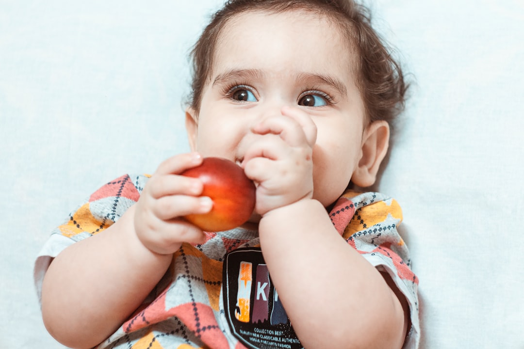 girl in white and red stripe shirt holding red apple