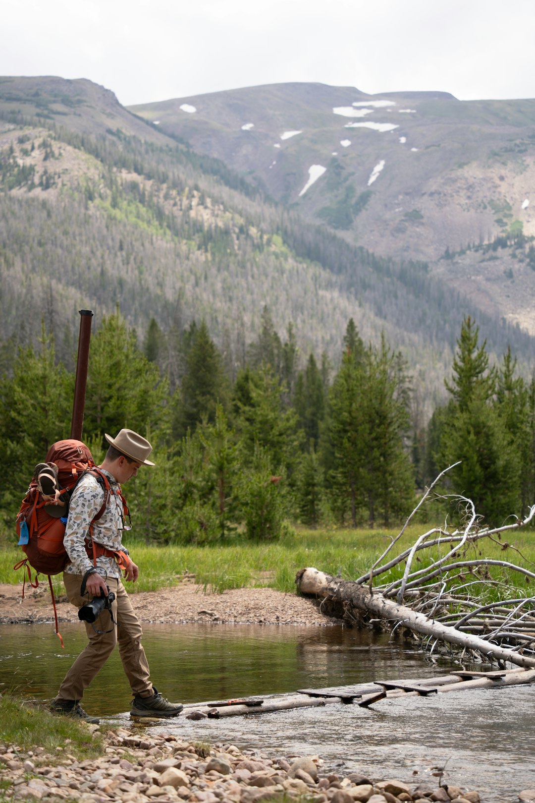 A man with a backpack crossing a stream