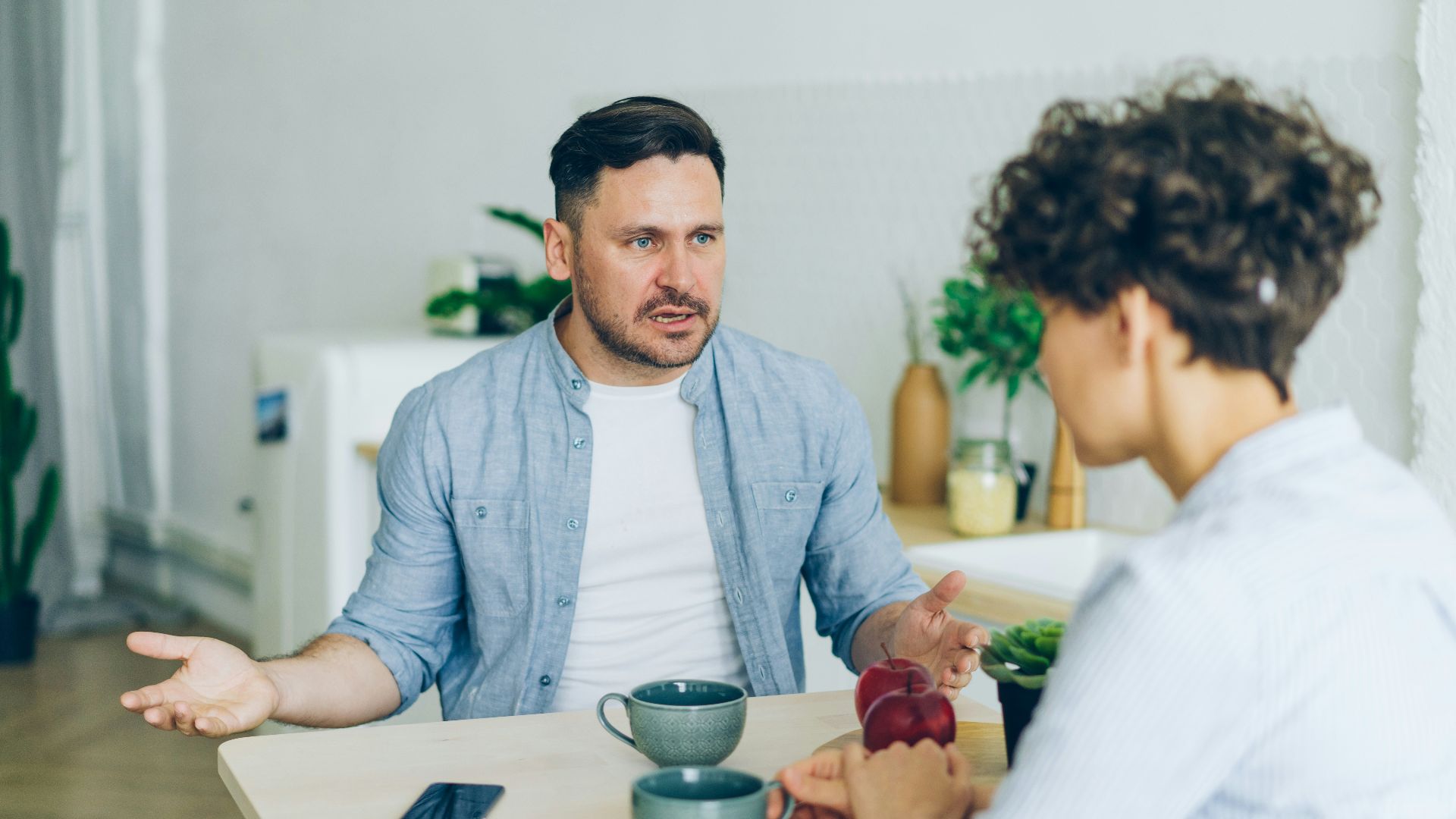 a man sitting at a table talking to a woman