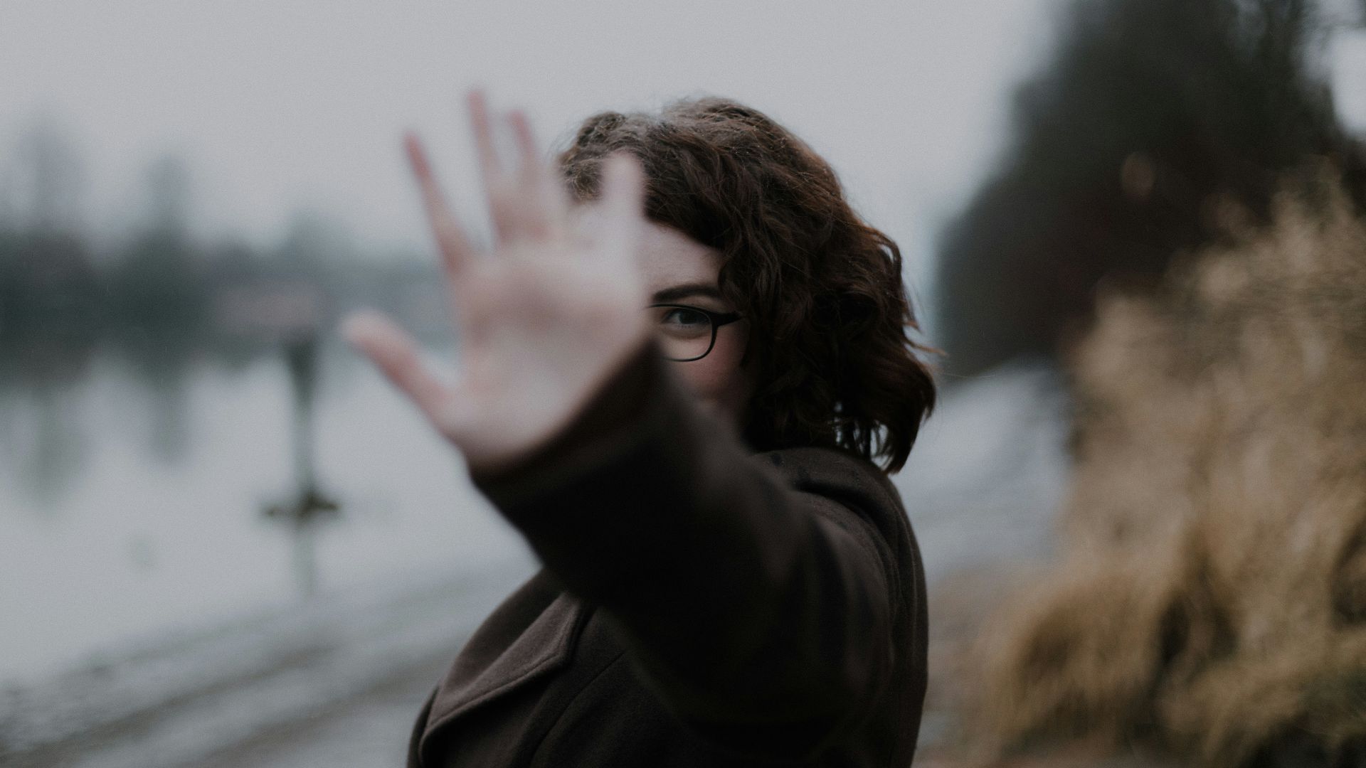 woman in black coat standing near body of water during daytime